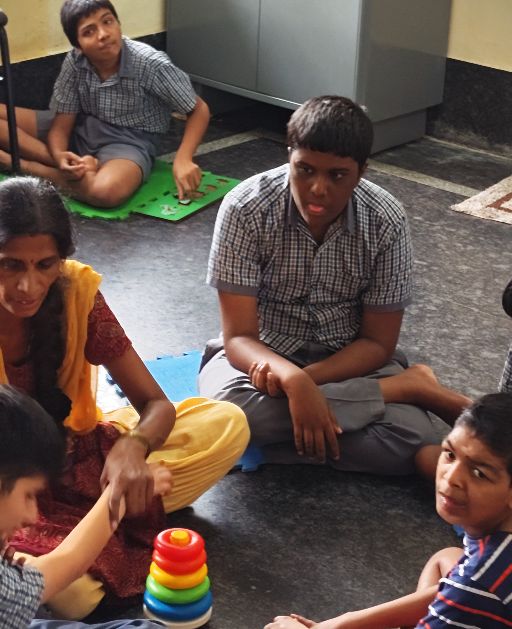 A teacher working with students using learning toys at Navachethana
